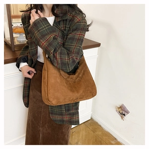 Detail of brown suede shoulder bag with minimalist curved design and soft matte finish