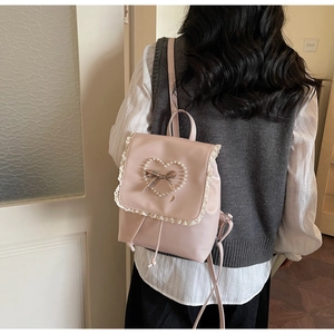 Vue détaillée du sac à dos rose avec bordure en dentelle et cœur en perles sur un mannequin