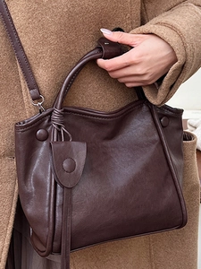Deep brown matte leather tote bag with elegant knot pendant and shoulder strap