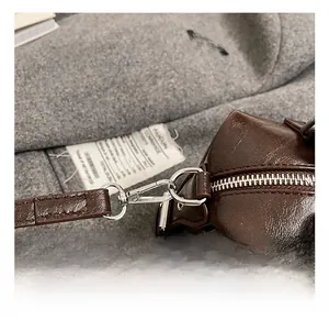 Detail view of the silver metal swivel hook and zipper closure on a dark brown Boston bag