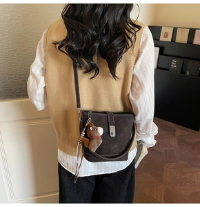 Detail view of dark brown bucket bag with silver buckle and cute horse plush charm accessory