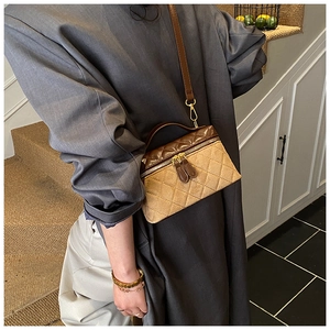 Detail of quilted leather crossbody bag with dual zippers and gold hardware accents