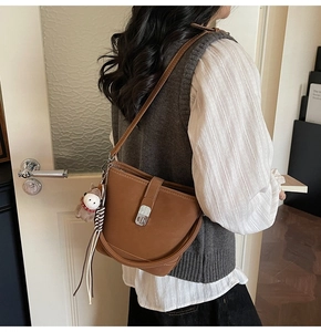 Detail of a brown leather hobo bag with silver twist lock and plush puppy charm