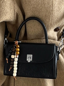 Chic black leather crossbody bag with silver lock and decorative beads on wool coat