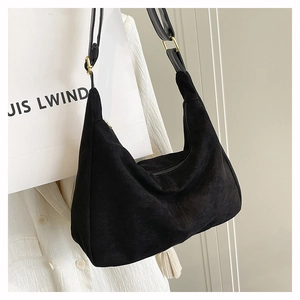 Detail of black suede hobo shoulder bag with adjustable leather strap and gold buckle hardware