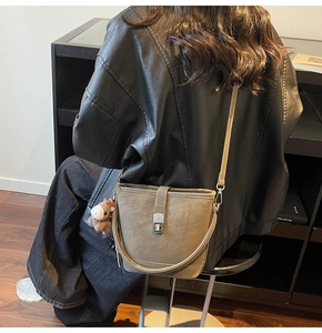 Close-up of retro taupe bucket bag featuring a metal twist lock and cute horse charm