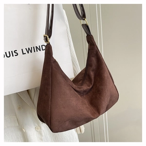 Detail of brown suede hobo bag with dark leather strap and gold metal buckle