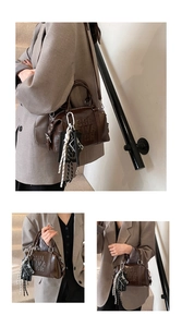 Detail of vintage brown leather Boston bag with COL TIVA TOR embossed text and camera charm