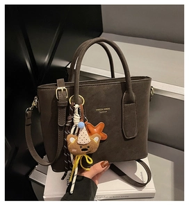 Détail du sac fourre-tout marron moka en cuir mat avec un pendentif d'ours décoratif