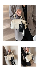 Detail of cream Boston bag with embossed lettering and stylish plaid ribbon pendant