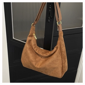 Detail of a brown vintage crescent hobo bag with suede texture and gold zipper hardware