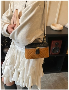 Quilted two-tone crossbody bag shown on a model with grey sweater and lace skirt
