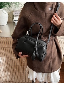 Detail der Boston-Tasche aus schwarzem Lychee-Leder mit Knotengriff und Schultergurt
