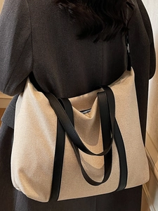Minimalistische große beige Canvas-Tragetasche mit schwarzen Trägern an einem Model