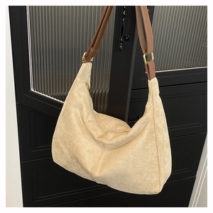 Detail of beige suede hobo bag featuring brown leather strap and gold metal hardware