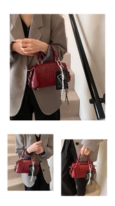 Close-up of red glossy leather Boston bag featuring embossed BBL letters and dual handles