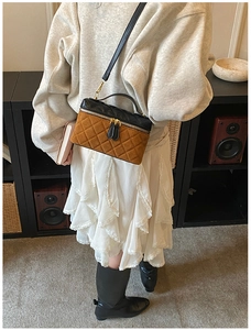 Detail view of quilted black and brown crossbody bag shown on a model in a retro setting