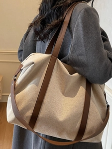 Große beige Canvas-Tragetasche mit braunen Lederriemen an der Schulter des Models