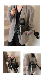 Detail of black Boston bag featuring embossed text and woven shoulder strap in macro view