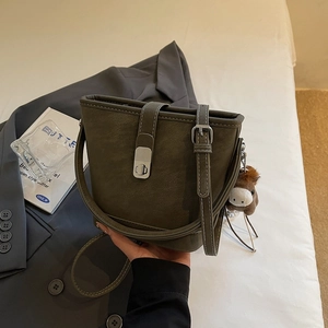 Detail of dark green leather bucket bag with silver clasp and small horse pendant