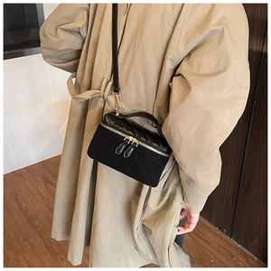 Detail of black quilted leather vanity bag with gold dual zippers and top handle strap