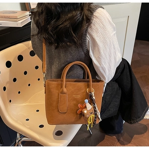 Vue détaillée du sac cabas marron avec breloque ours et bandoulière réglable