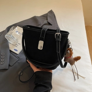 Detail of black bucket bag with white stitching, silver hardware and a horse charm