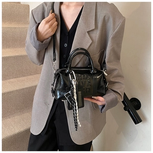 Detail of black glossy leather Boston bag featuring 3D embossed letters and side strap charms