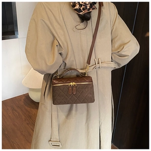 Brown quilted vanity bag with metal zipper shown on a model in a khaki trench coat