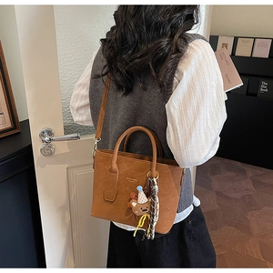 Détail du sac bandoulière marron avec pendentif ours et foulard décoratif