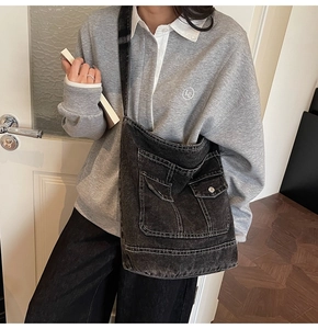 Dettaglio della borsa a tracolla vintage in denim nero con tasche utility sul modello