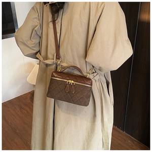 Detailed close-up of dark brown quilted crossbody bag with dual-material texture and gold zipper