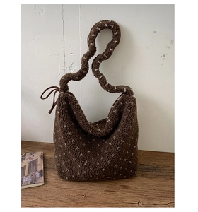Detail of dark brown plush tote bag with white dots on a rustic wooden table surface