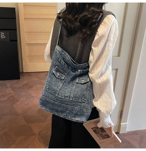 Dettaglio borsa tote in denim blu con tasche cargo e bottoni metallici sulla modella
