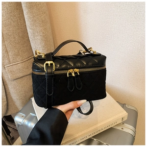 Close-up of black quilted small square bag with gold hardware and dual-material texture