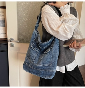 Dettaglio di una grande borsa hobo in denim con tasche frontali e tessuto in jeans lavato