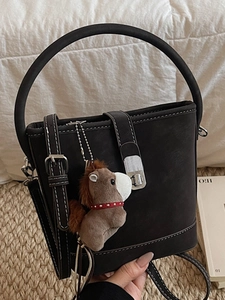 Retro black bucket bag with white contrast stitching and a brown plush horse charm