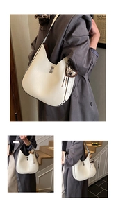 Detail of white textured hobo bag with silver buckle and leopard print charm accessory