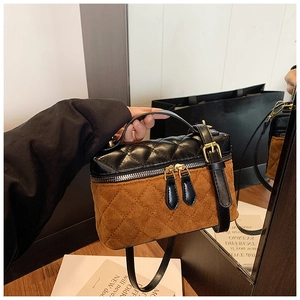 Detail view of the black and brown patchwork quilted handbag with golden zipper details