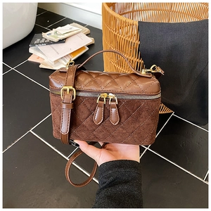 Detail of brown quilted crossbody bag with suede texture and gold hardware zipper