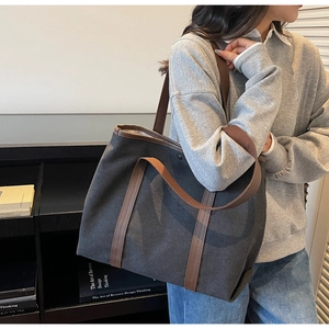 Grand sac cabas en toile grise avec anses en cuir marron porté par un mannequin