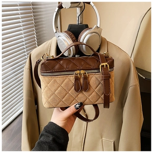 Detail of brown quilted patchwork camera bag with leather finish and metallic zip