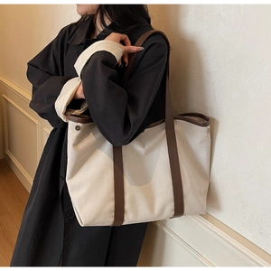 Détail du sac cabas en toile crème avec poignées en cuir marron et rivet métallique élégant
