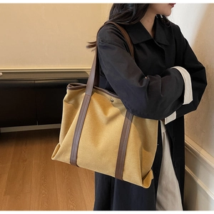 Détail d'un sac cabas en toile moutarde avec anses en cuir marron dans un décor minimaliste