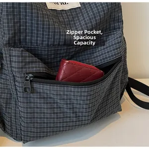 Detailed view of plaid backpack front pocket with zipper and interior storage capacity