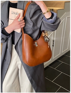 Detail view of brown leather tote featuring leopard print bow and heart pendant