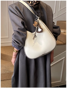 Close-up of white pleated leather hobo bag with heart mirror and leopard fur charm