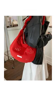 Red oversized shoulder bag with floral bird embroidery and pleated strap on model