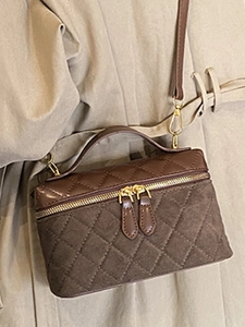 Quilted dark brown crossbody bag with gold hardware shown on a trench coat