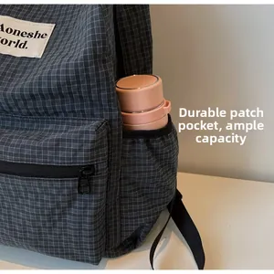 Detail of grid pattern backpack with side elastic pocket holding a water bottle